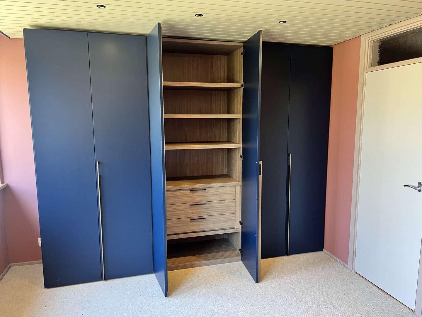 Dezelfde kast met twee deuren open: lichte houten legplanken en drie laden