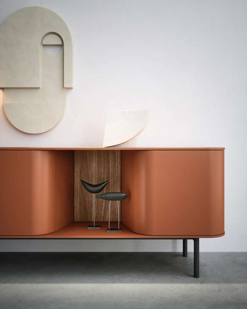 Gebogen terracotta dressoir met een open notenhouten vak tegen een witte wand